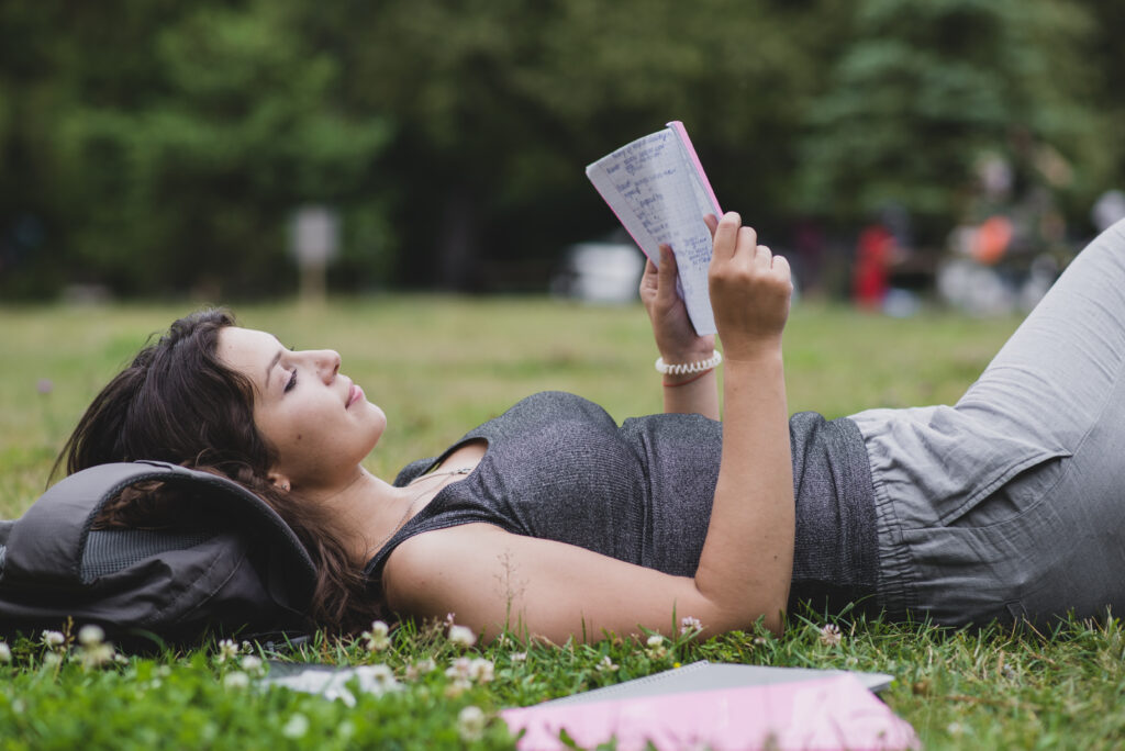 girl lying grass park reading